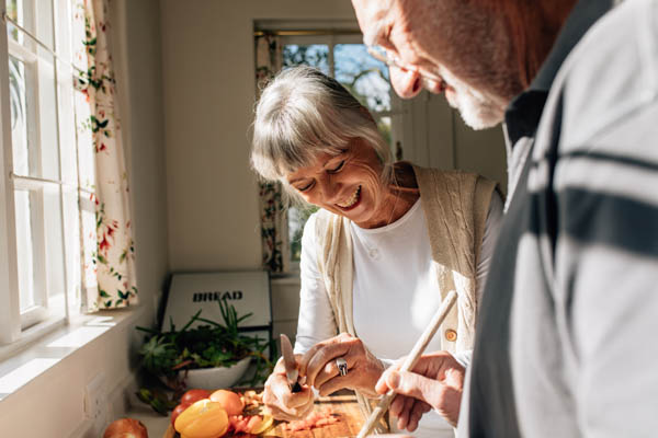 Happy senior couple making food standing in kitchen